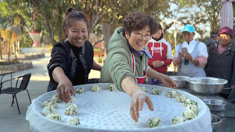 【2】旅居者趙發(fā)英（圖左二）教曼海村村民做花卷。陶思源-攝